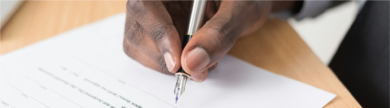 photo of a hand signing a contract
